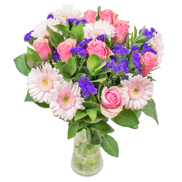 An elegant floral ensemble arranged by Sydenham Hill Florist, this bouquet is a celebration of soft pinks and bold purples, captured in a tall, clear glass vase. At its heart are approximately seven to nine roses in shades of gentle blush and rose-petal pink-their petals coiled in classic spirals or softly beginning to bloom. Surrounding them, five to seven pale pink gerbera daisies display their signature wide heads and fine, radiating petals, accented by nearly-white centers. Throughout the bouquet, clusters of vibrant purple statice mimic the wild bursts of summer flowers found across the Sydenham Hill Wood, adding both colour and texture. The rich, deep green foliage forms a beautiful base, highlighting the vibrancy of the blooms and bringing a natural serenity to the design. The visible stems and water within the vase reinforce the feeling of freshness and care that defines every delivery here in Sydenham Hill. Perfect as a gift for birthdays, anniversaries, Mother's Day, or as a heartfelt decorative accent for home or office, this arrangement exudes elegance, celebration, and affection-an enduring reflection of floral artistry tailored for the local community.